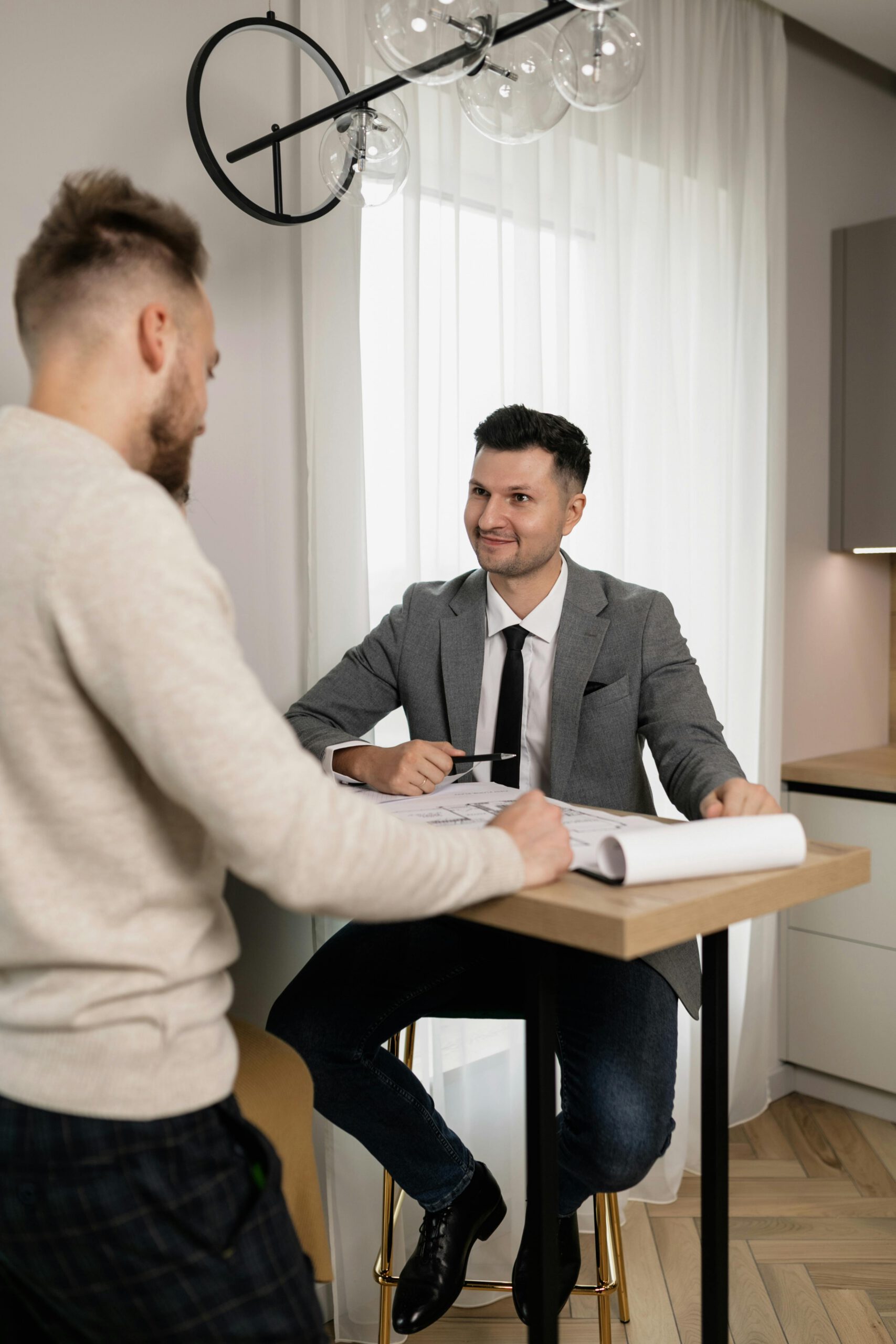 Real estate agent discussing floor plans with a client indoors.